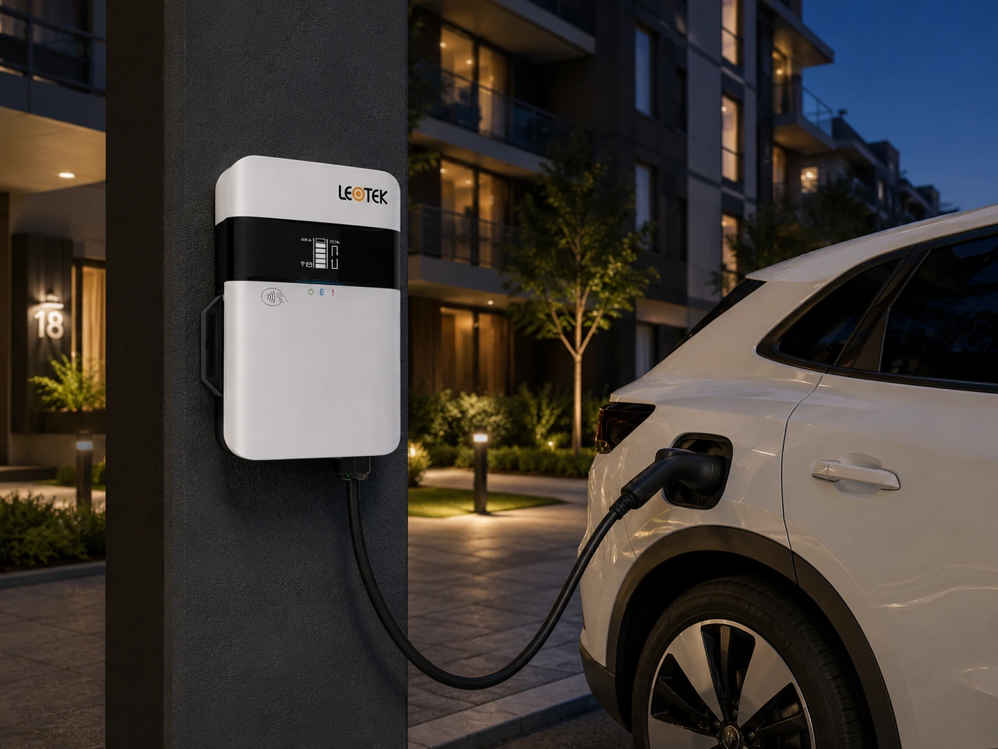 Wall-mounted LEOTEK EV charger beside an electric vehicle at a residential apartment building at dusk