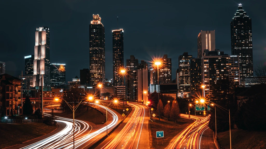 Illuminated city skyline and roadway streetlights at night.