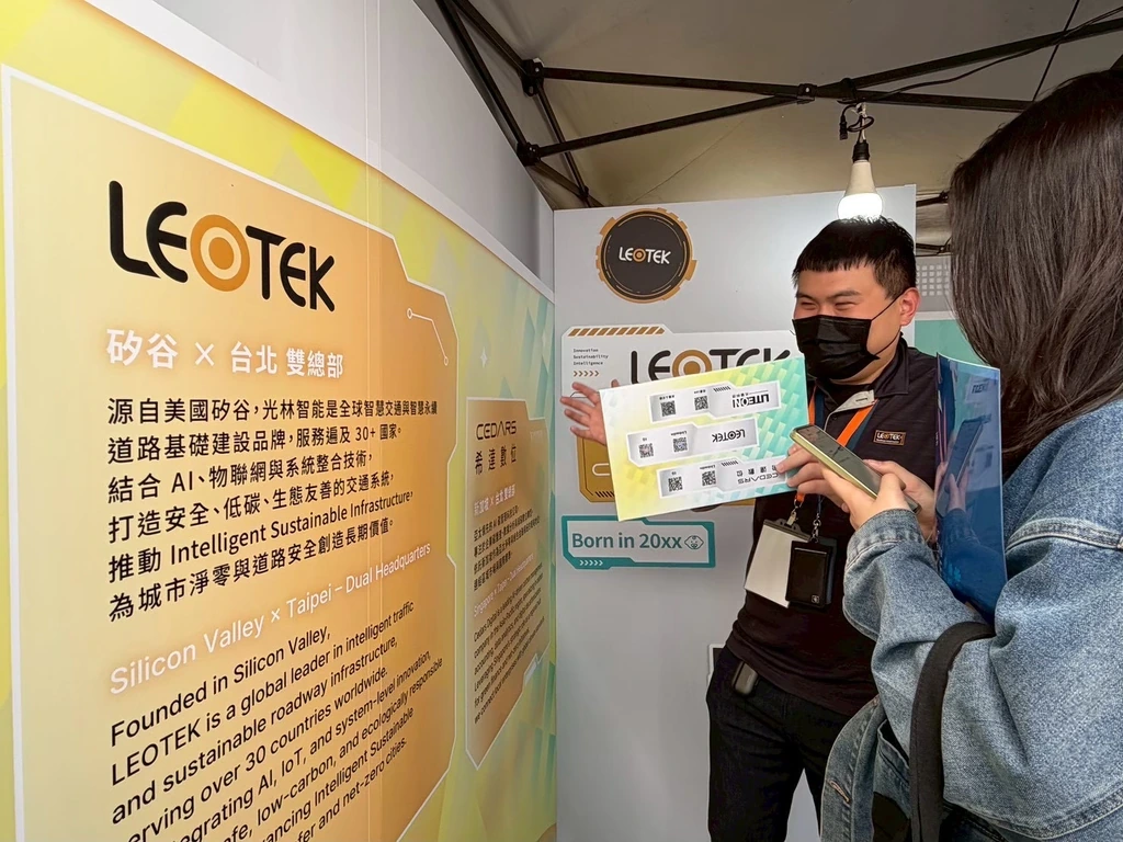 LEOTEK representative explaining lighting technology to a visitor at an exhibition booth