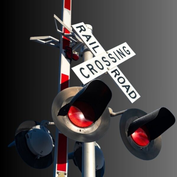 Angled view of a railroad crossing crossbuck and red signals.
