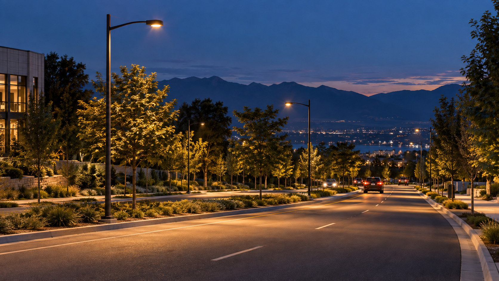 Shielded streetlights along a landscaped road near buildings at dusk, viewed from the travel lane