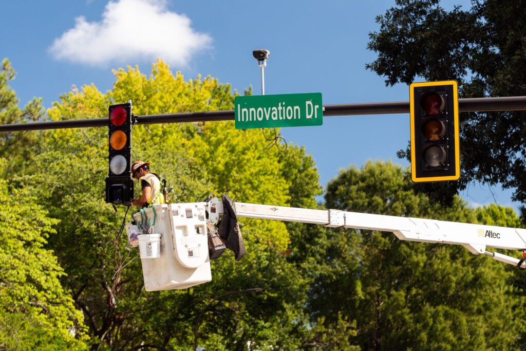 The Interlux AI Traffic Signal System is deployed at Curiosity Lab in Peachtree Corners, Georgia, as a technician installs and adjusts traffic signal equipment from an aerial work platform at the Innovation Drive intersection.