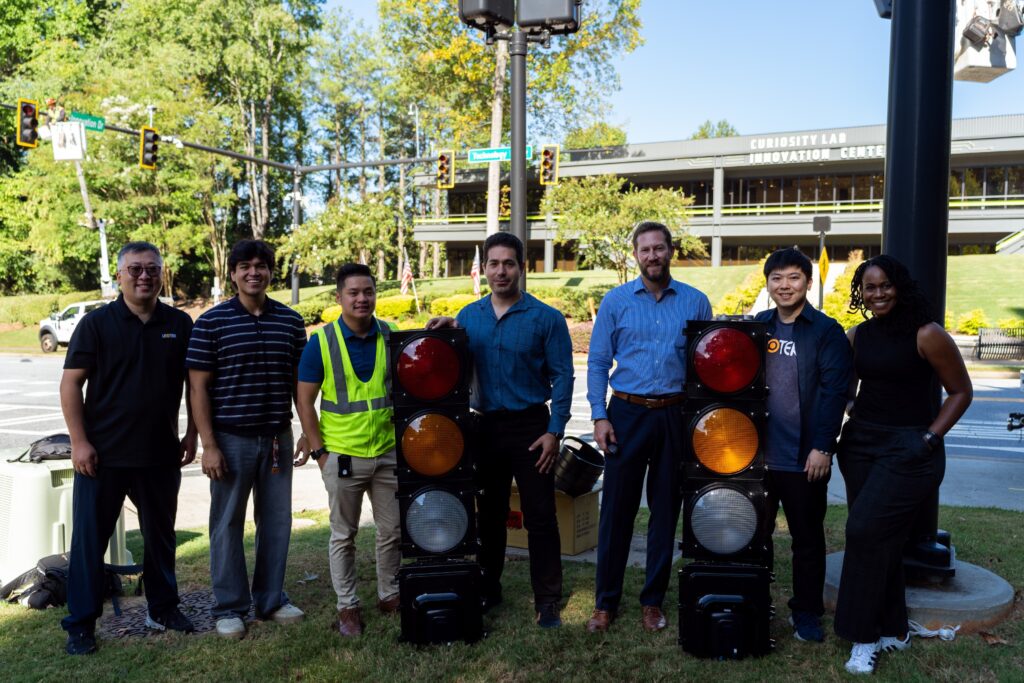 Team members from LEOTEK, Curiosity Lab and the City of Peachtree Corners stand beside two Interlux AI traffic signal units, marking the completion of the system’s deployment and the start of real-world traffic evaluation.